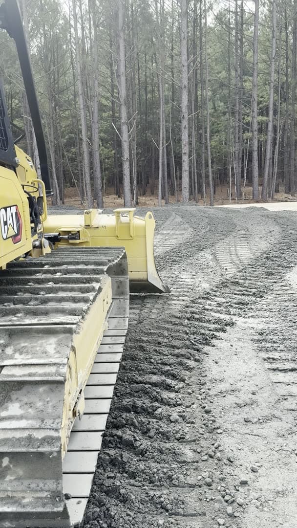 Ward Excavation CAT dozer with raised blade pushing fresh-graded dirt at a Carolina pine jobsite.