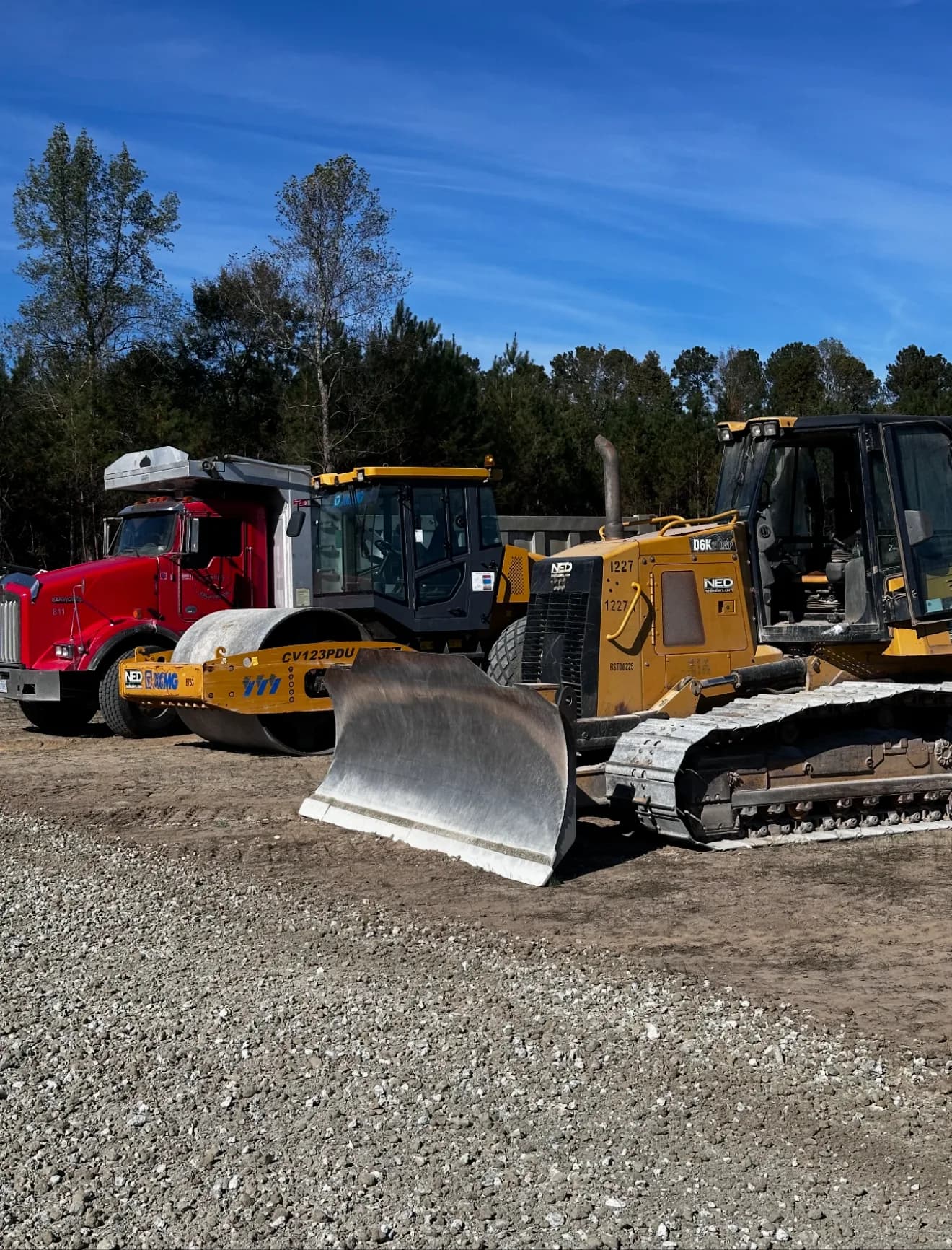 Ward Excavation equipment fleet — Kenworth dump truck, roller, and CAT track loader — at the company's Whiteville, NC yard.