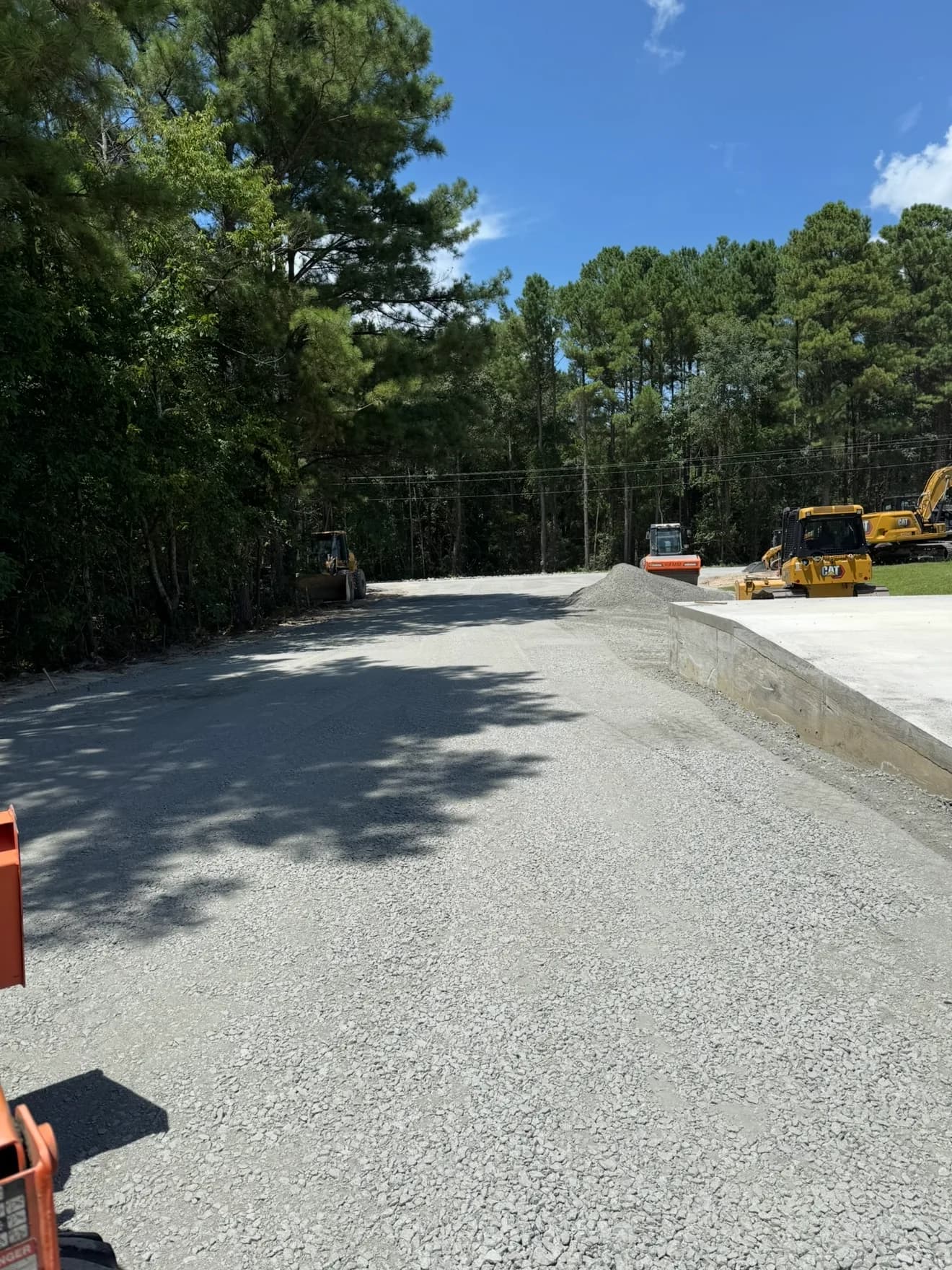 Freshly graded gravel pad with a new concrete curb at a Ward Excavation commercial site in the Carolinas.