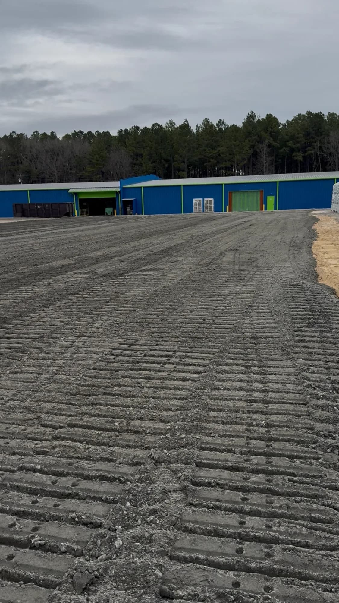 Compacted, graded pad in front of a commercial metal building on a Ward Excavation site-work project.