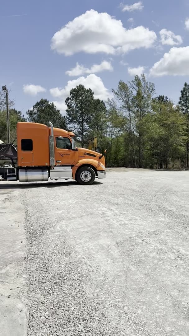 Orange Ward Excavation hauling truck parked in the company yard with an excavator behind it.
